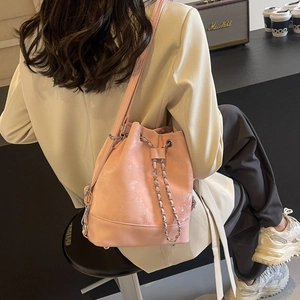 Stylish pink bucket bag with silver chain drawstring shown in a minimalist lifestyle setting