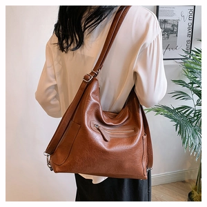 Borsa marrone in pelle cerata indossata da modella mostra la texture e la grande capacità