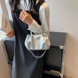 Silver pleated cloud handbag with metallic finish and chain strap worn by a model