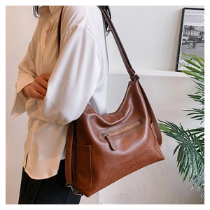 Dettaglio borsa hobo vintage marrone scuro con cerniera e tracolla su camicia bianca