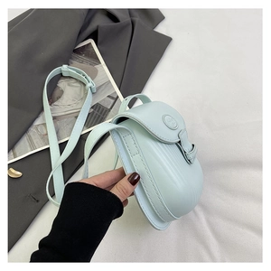 Detail of mint green crossbody saddle bag with flap closure and embossed logo detail