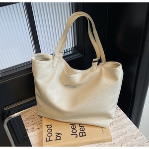Close-up of the large cream tote bag with litchi texture and silver metal hardware detail