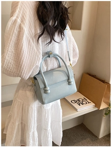 Détail du sac à main carré en cuir bleu clair avec des poignées décoratives sphériques