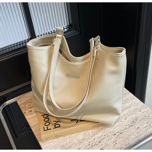 Detail of soft cream leather tote bag featuring a silver metal bar on a marble surface