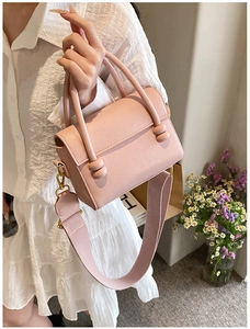 Détail du sac à main rose en cuir grainé avec large bandoulière et boucles décoratives
