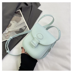 Detail view of mint blue small crossbody bag showing vertical textured patterns and metallic logo