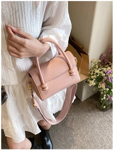 Détail du sac à main en cuir rose avec poignée nouée et large bandoulière textile