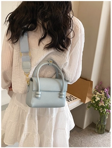 Détail du sac bandoulière bleu clair à motif litchi avec large sangle tissée et dorures