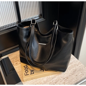 Close-up of black lychee texture tote bag with silver bar and thin shoulder straps