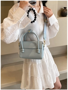 Gros plan du sac à main bleu clair en cuir grainé avec une large bandoulière réglable