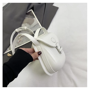 Detail of ivory leather crossbody bag featuring a flap closure and adjustable strap