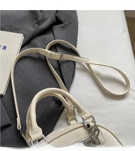 Detail of adjustable long shoulder strap with silver hardware on cream white bag