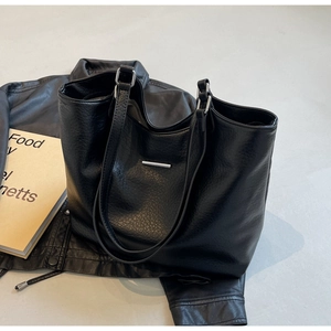 Detailed view of black minimalist tote bag with silver metal bar and leather texture