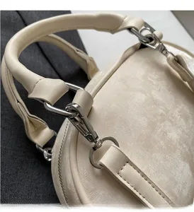 Detailed close-up of high-quality silver metal hardware and stitching on a beige handbag