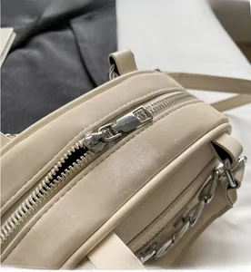 Detailed close-up showing smooth silver metal zipper on cream white leather handbag
