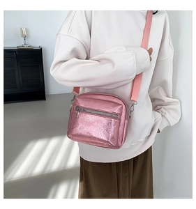 Detalle de un bolso bandolera rosa metalizado láser con dos compartimentos con cremallera