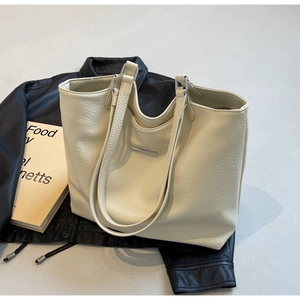 Close-up of minimalist cream tote bag showing soft lychee texture and metal detail