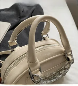 Detail of cream boston bag showing cylindrical dual handles and silver metal zip closure