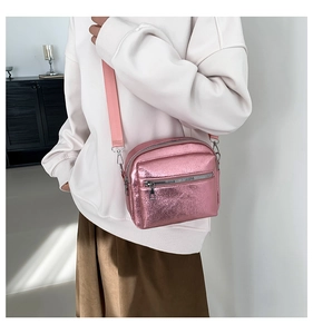 Detalle de bolso bandolera rosa metalizado con cremalleras dobles y correa de tejido