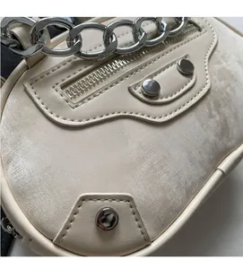 Detail of beige faux leather handbag featuring silver motorcycle style hardware and chain