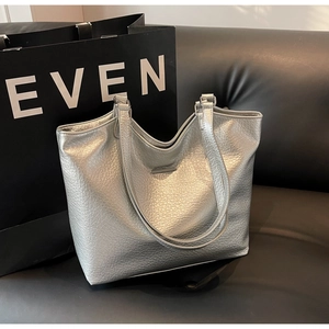 Macro detail of silver pebbled leather tote bag texture with sleek metal bar ornament