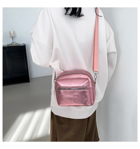 Detalle del bolso bandolera rosa metalizado con cremalleras plateadas y correa tejida