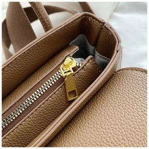 Détail de la fermeture éclair dorée et texture cuir grainé d'un sac à main marron