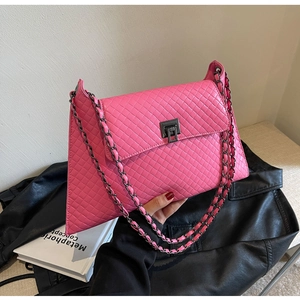 Detail der leuchtend rosa gewebten Ledertasche mit dunkler Kette und Drehverschluss