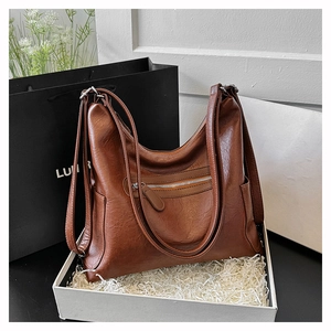 Dettaglio della borsa tote in pelle marrone scuro con cerniere argentate in confezione regalo