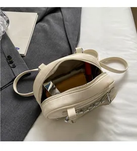 Top-down macro view of compact cream handbag showing interior storage and silver chain strap