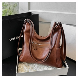 Dettaglio della borsa tote in pelle marrone scuro con zip argentate in scatola regalo