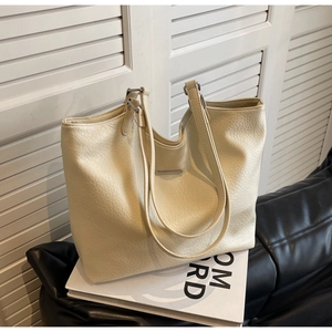 Close-up of the pebbled leather texture and silver metal hardware on a cream tote bag