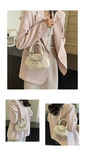 Detail of cream half-moon handbag featuring vintage silver studs and chain decoration