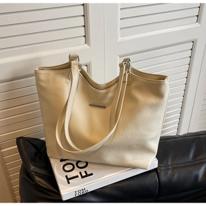 Detailed macro view of the beige lychee pattern leather tote bag with silver metal bar