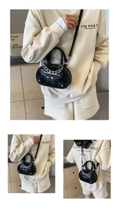 Detail of black glossy leather mini bag with silver chain and studded biker style accents
