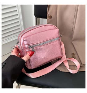 Detalle del bolso bandolera rosa metalizado con cremallera doble y correa de tela ajustable
