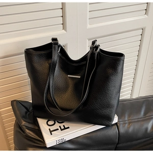 Detail of black pebbled leather tote bag with silver metal bar and large capacity
