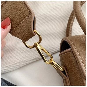 Détail d'un sac à main en cuir marron foncé avec fermoir doré et anneau métallique