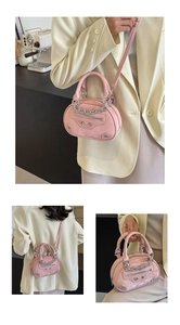 Pink semi-circular handbag with silver chain and rivet details shown on a model