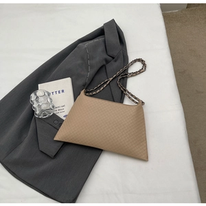 Detailansicht der gesteppten beigen Shopper-Tasche auf grauem Anzug mit Kette
