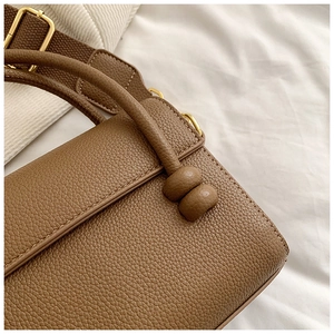 Détail du sac à bandoulière en cuir avec sangle tissée et ferrures dorées