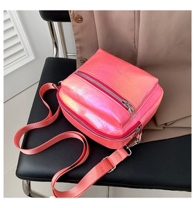 Bolso bandolera vertical rosa con cremallera doble y correa ancha sobre una silla