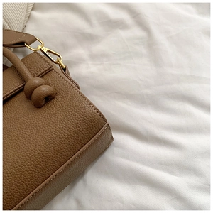 Détail du sac à main en cuir marron avec surpiqûres blanches et fermoir en métal doré