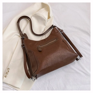 Dettaglio della borsa a tracolla vintage in pelle PU marrone su una giacca blazer bianca