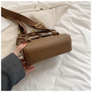 Vue détaillée du sac marron en cuir grainé avec une large bandoulière tissée chic