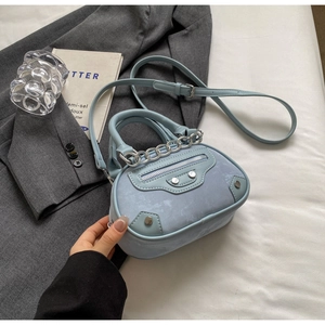 Close-up of light blue mini half-moon crossbody bag with silver studs and chain detail