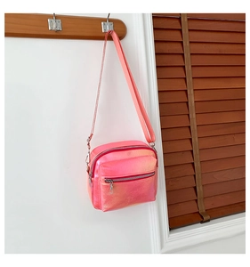 Detalle del bolso bandolera rosa láser con cremallera doble sobre una pared blanca