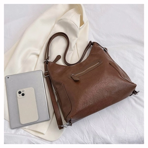 Dettaglio di una borsa tote marrone vintage con cerniera metallica e tasche laterali