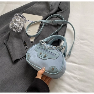 Detail shot of the light blue round crossbody bag featuring silver studs and zipper accents