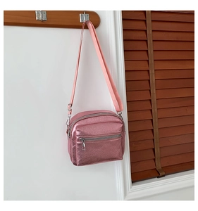 Detalle del bolso bandolera rosa metalizado con cremalleras plateadas y correa de tela